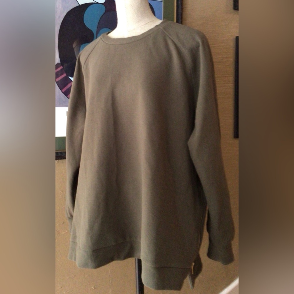Olive green sweatshirt with gold zipper detail.